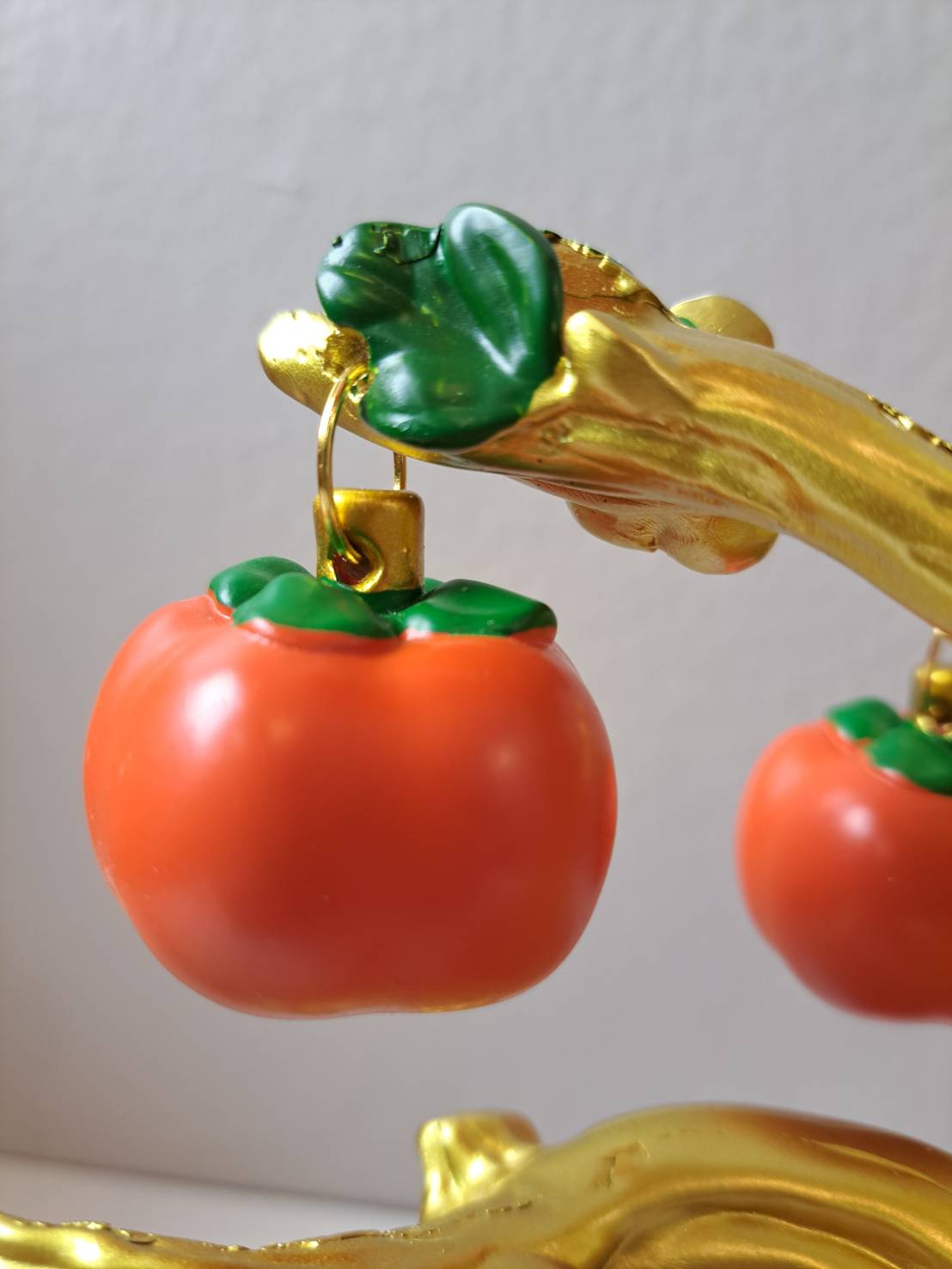 Close-up of red persimmon ornaments hanging from gold branches on Decorative Persimmon Tree CX618