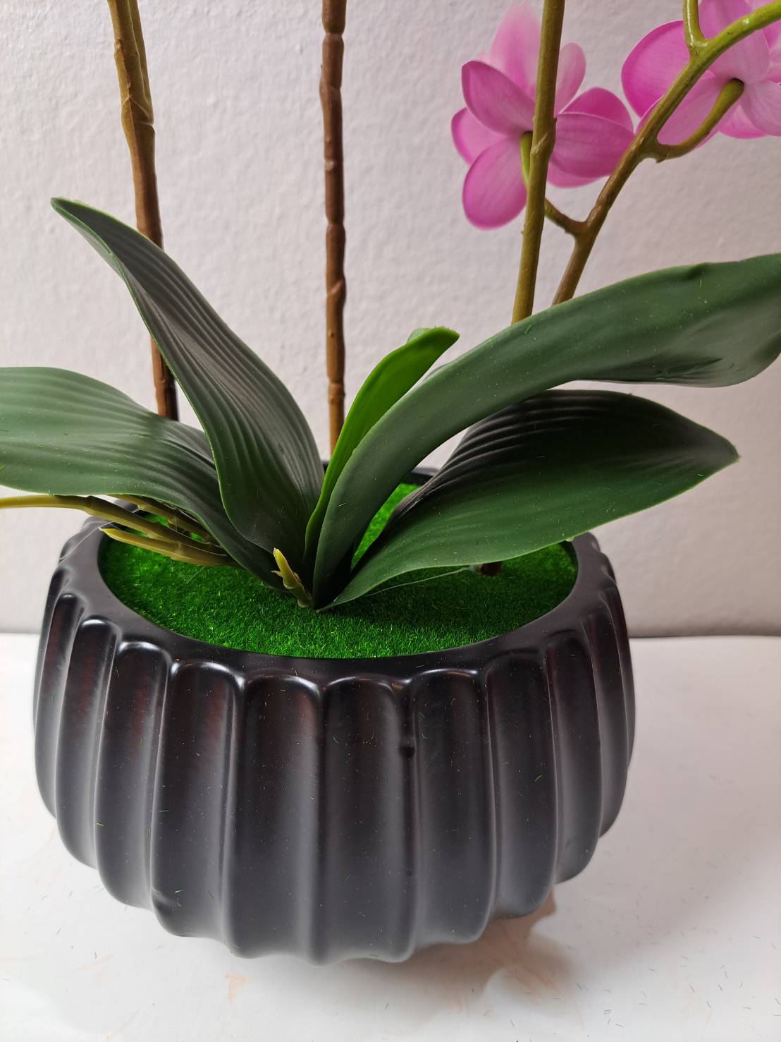 Faux magenta orchid in matte black ribbed ceramic pot with green moss base - FT254E