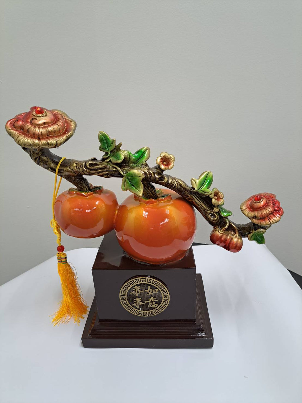 Close-up of two glossy orange persimmon fruits with green calyx on ML-363 branch figurine
