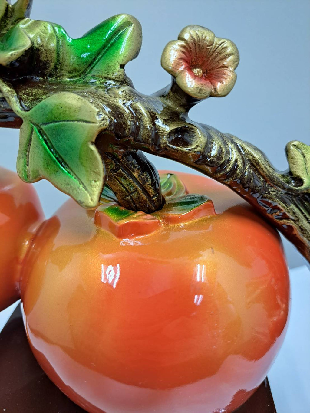 Detail of persimmon fruit surface with green calyx and gold-bronze branch texture on ML-363