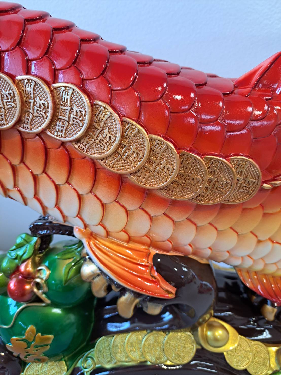 Base detail of JF7322-2 arowana statue showing jade green gourd, gold coins and dark wood-look platform