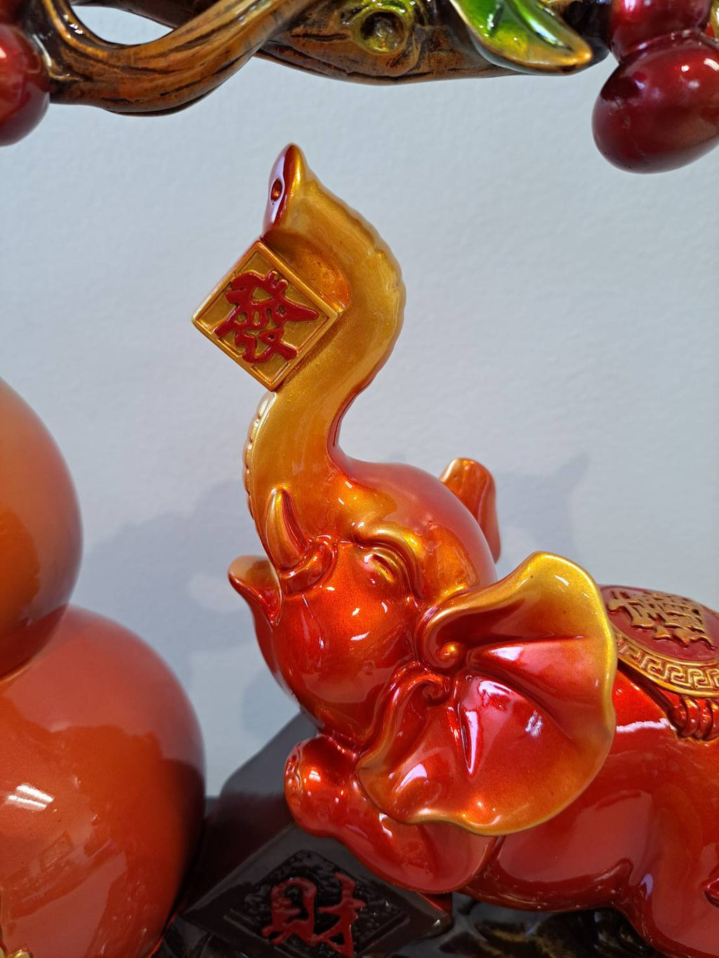 Close-up of red-orange elephant figurine holding gold 财 tablet on raised trunk in figurine 7314