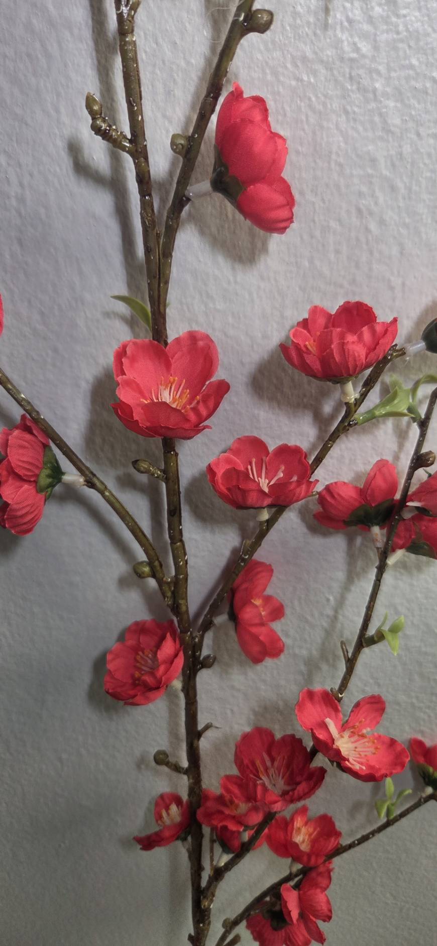 Faux red peach blossom branch close up detail