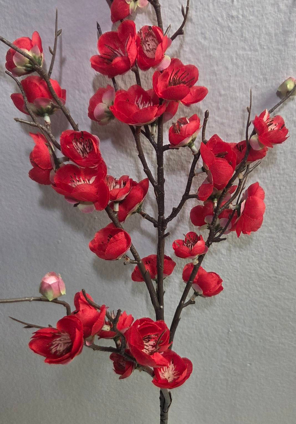 Faux red plum blossom branch close up detail
