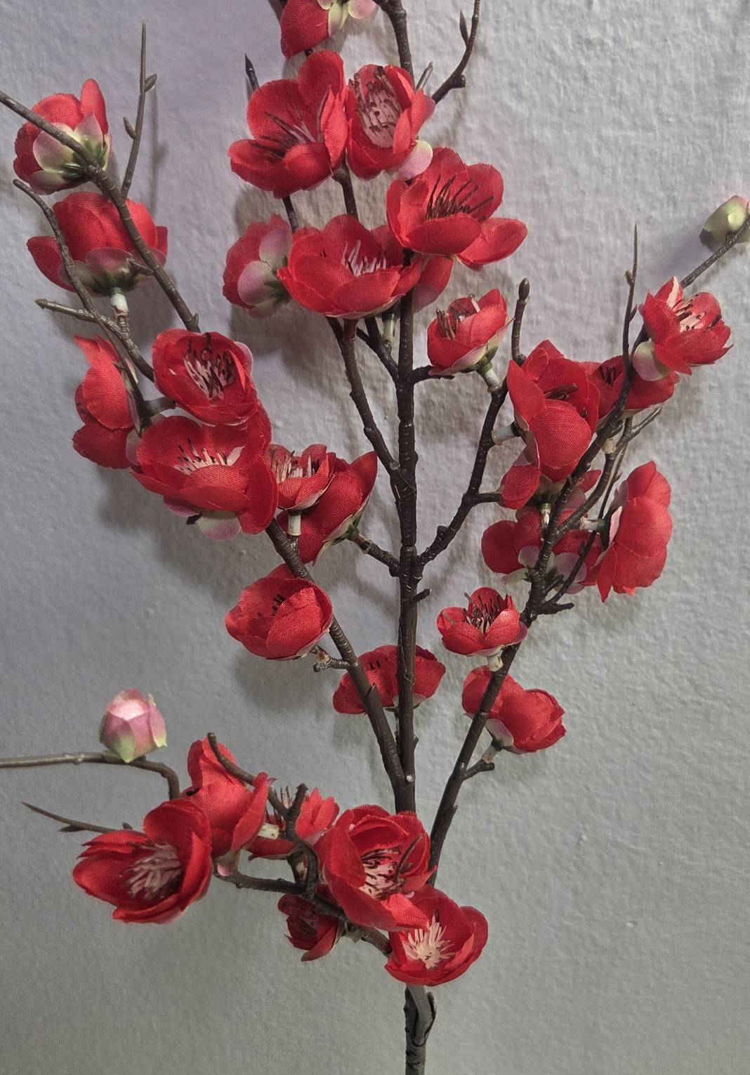 Faux red plum blossom branch close up detail