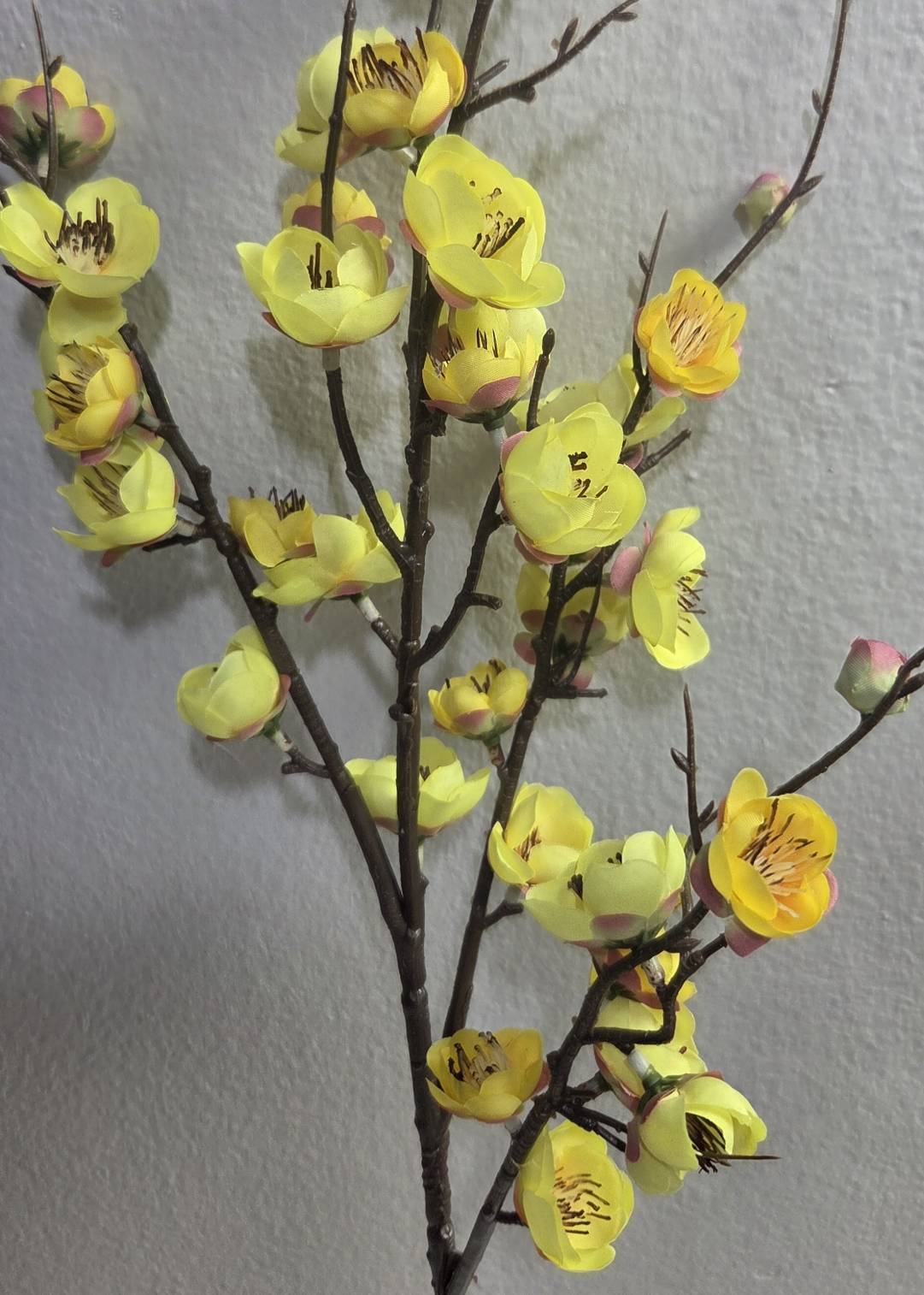 Faux yellow plum blossom branch close up detail