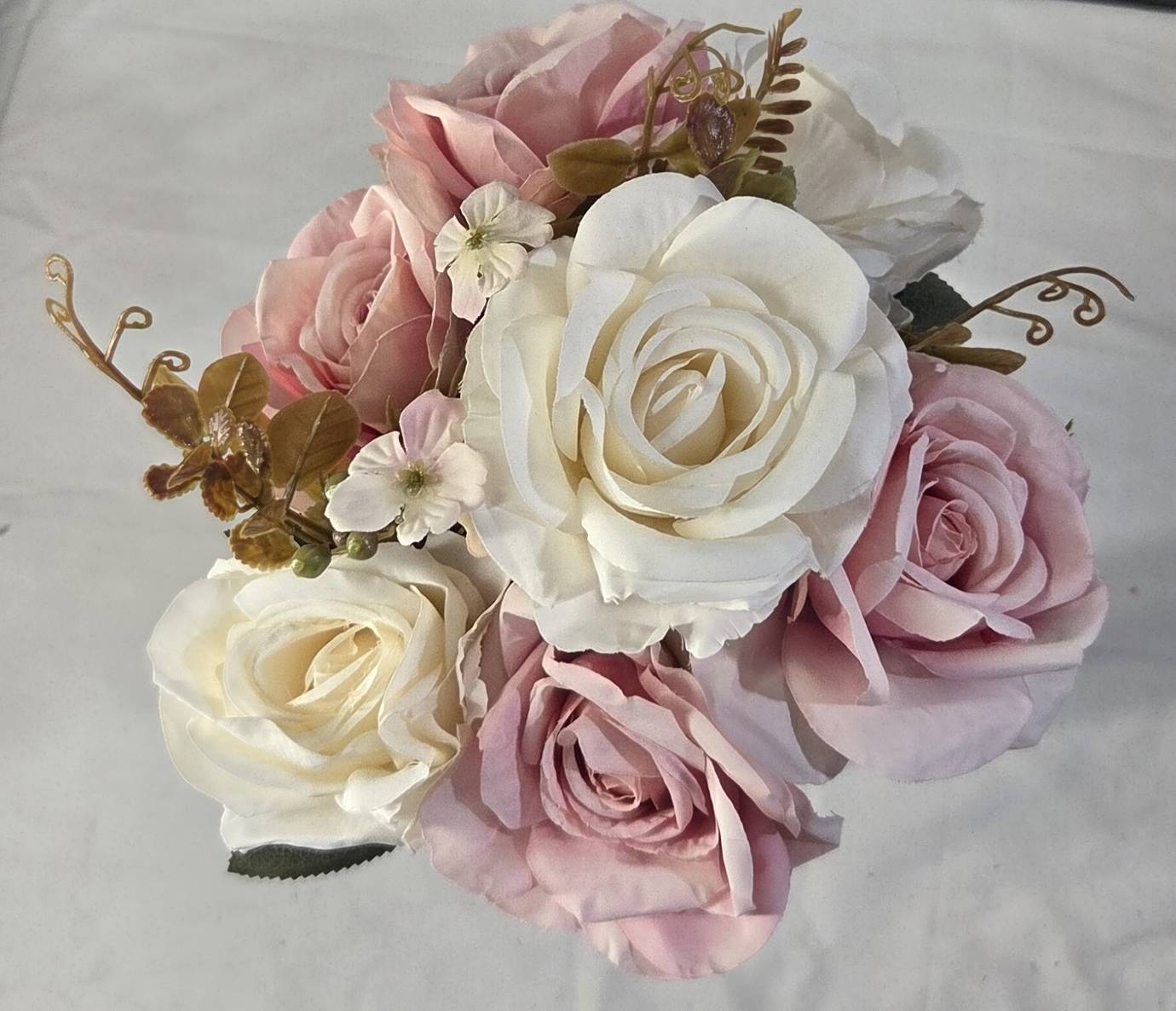 Faux white and pink rose bouquet displayed on white bookshelf with gold decor accents and coffee table books