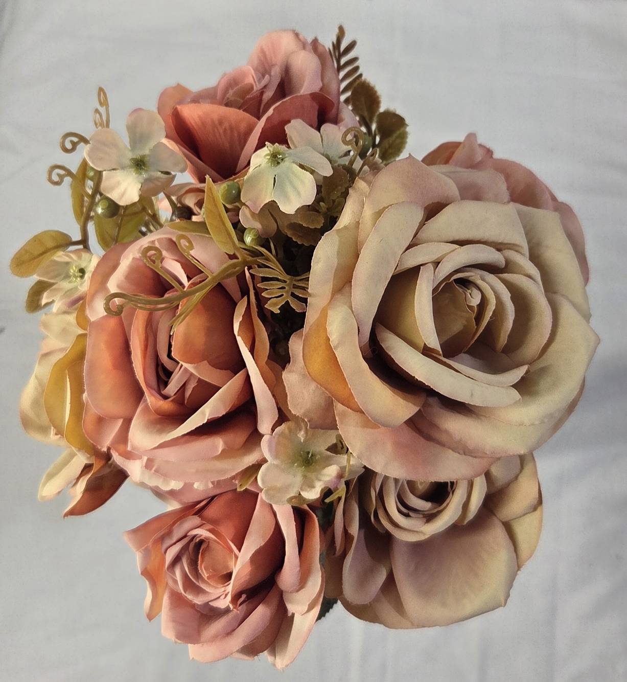 Close-up of faux champagne rose and dusty terracotta rose blooms with golden wire accents and white wildflowers