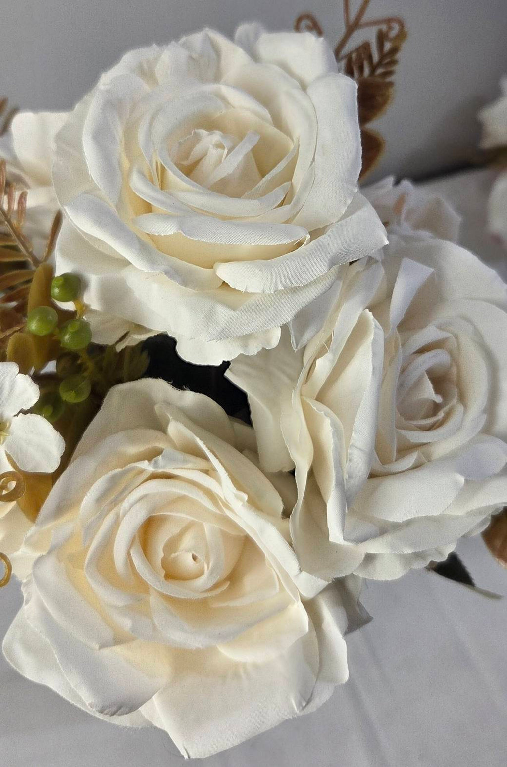 Close-up of faux ivory and cream rose blooms showing detailed layered petal texture and spiral center