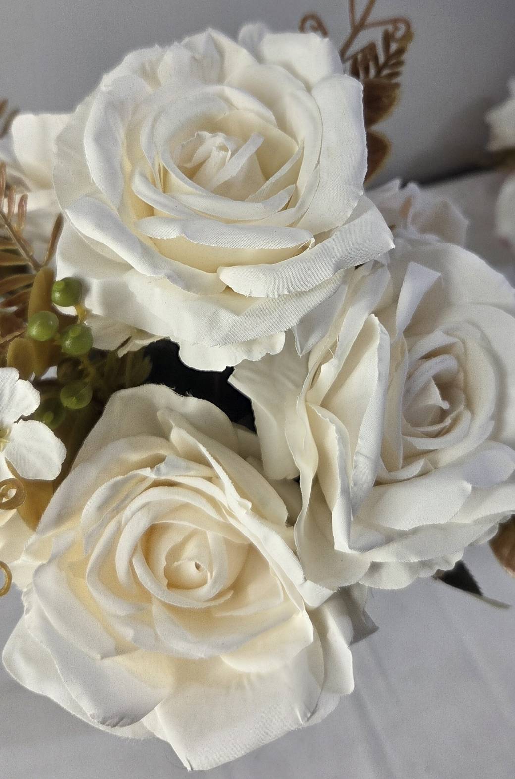 Close-up of faux ivory and cream rose blooms showing detailed layered petal texture and spiral center