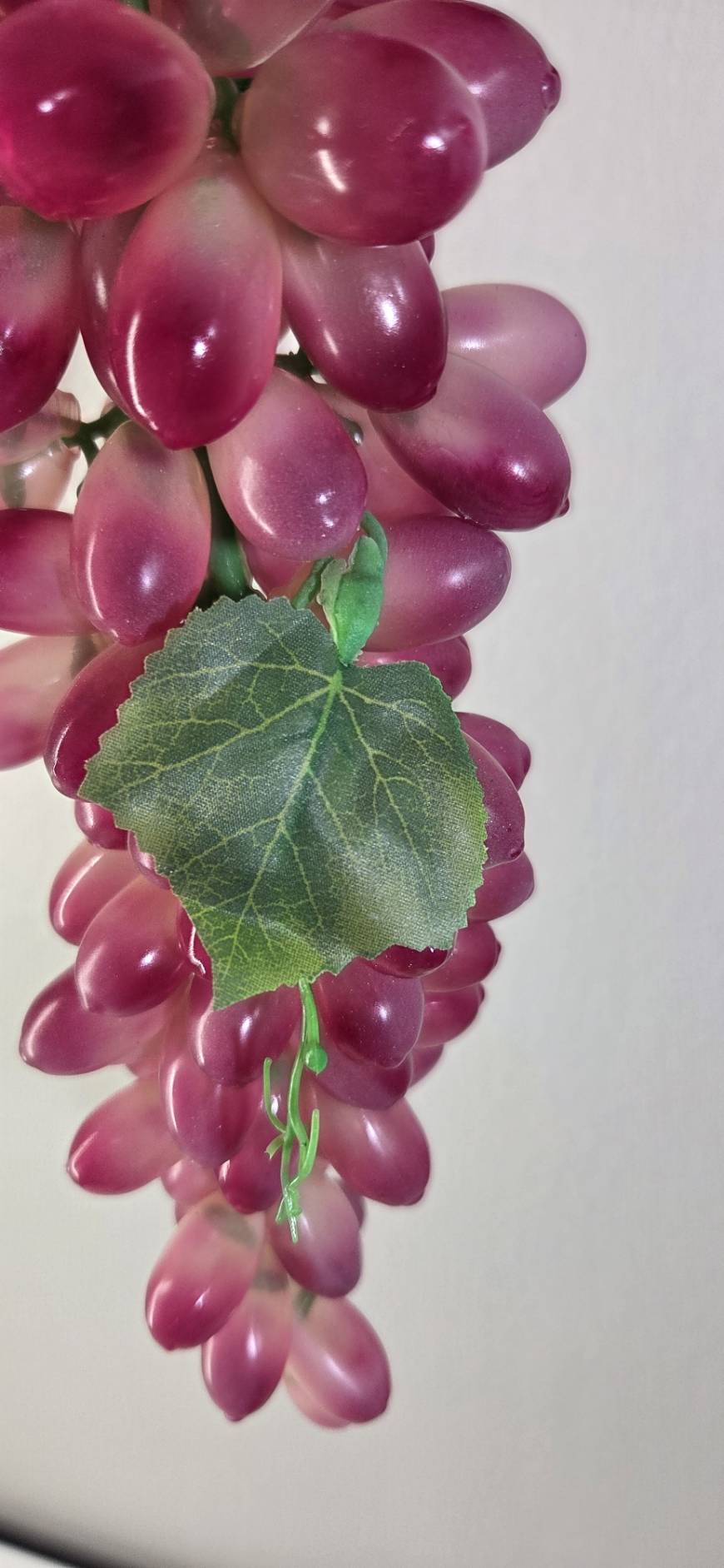 Faux Red Grape Cluster GRT-01 close-up - glossy deep red oval grapes with green hook hanger and faux vine leaves
