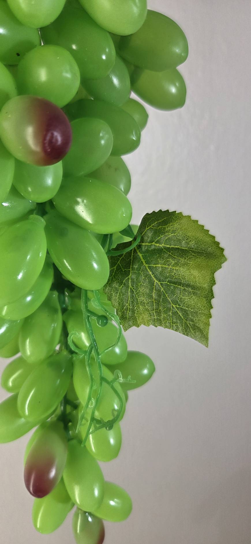 Faux Green Grape Cluster GRT-02 close-up - glossy bright green oval grapes with textured faux vine leaf and green curling tendrils