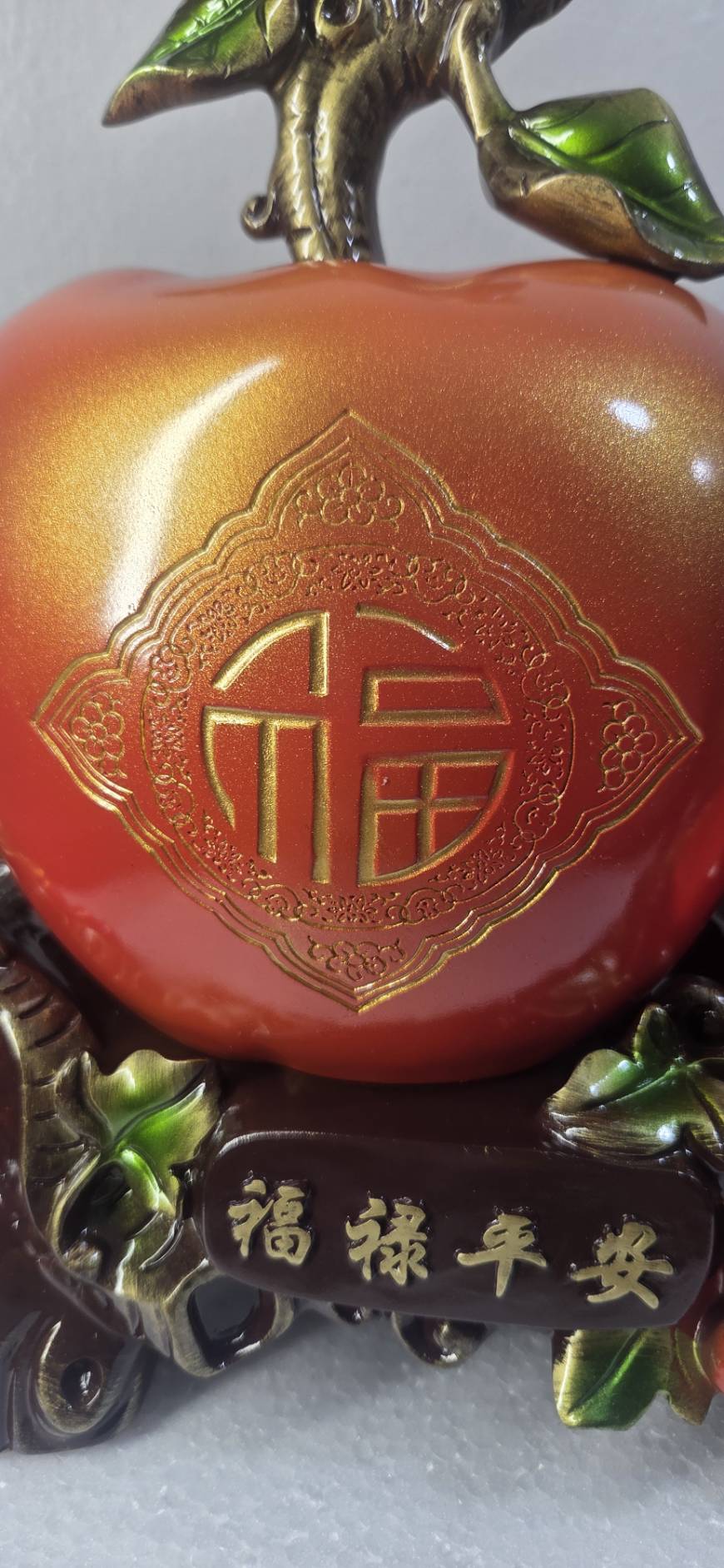 Detail of red cherry berry clusters with green leaves and gold-bronze branch on peach statue 7279