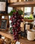 Faux Dark Purple Grape Cluster GRT-04 lifestyle - large artificial dark purple grape cluster displayed on rustic wooden coffee shop shelf beside coffee beans jar and espresso menu