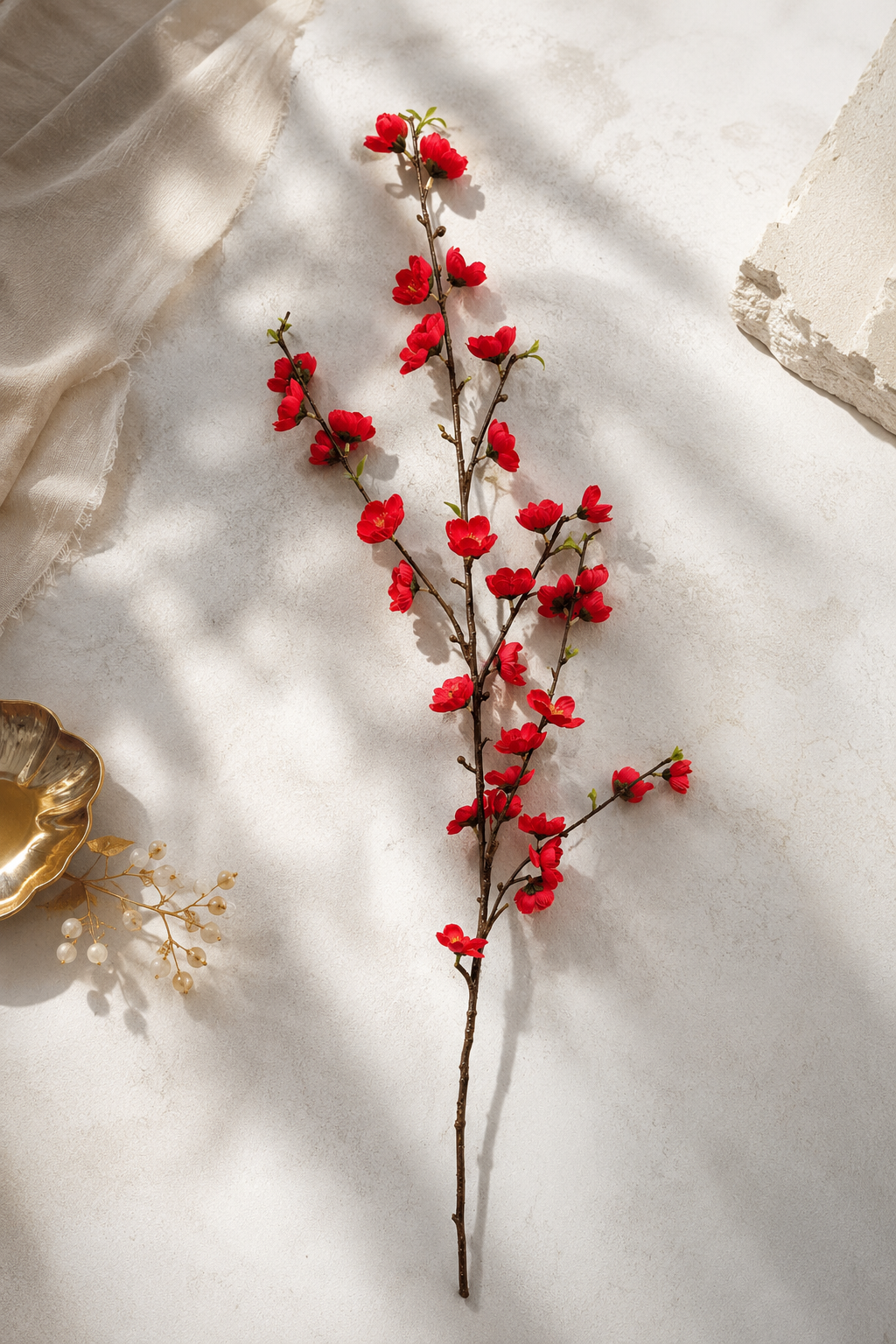 Red peach blossom branch flat lay on white linen - lifestyle